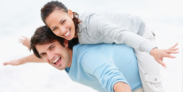 Female in business class wearing headphones looking at the screen in front of her with an open-mouthed smile